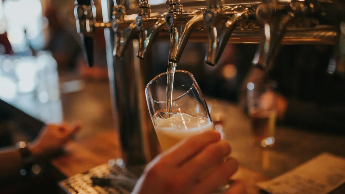 サーバーからグラスにビールを注いでいる手元