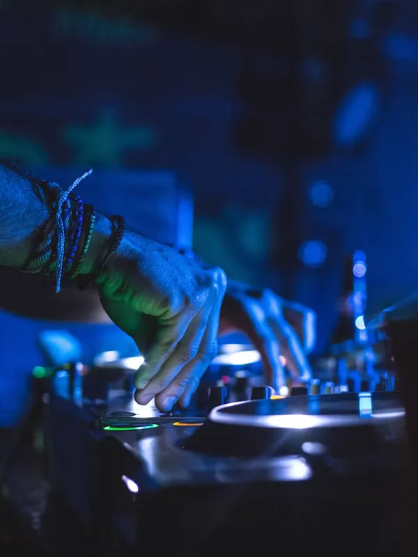 青い照明の中で DJ 機材を操作する手元