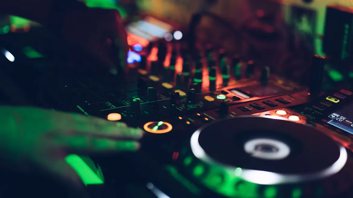 緑の照明に照らされた DJ 機材のジョグホイールと手元