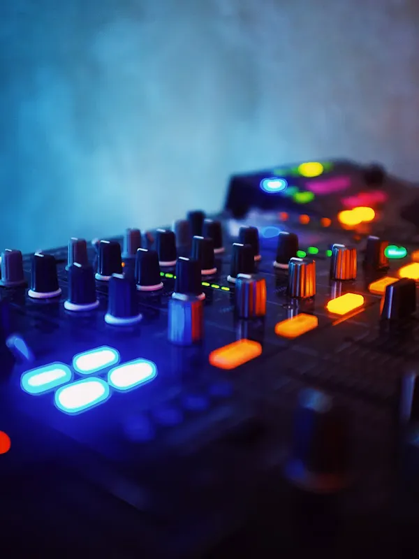 スモークの中で光る DJ ミキサーのつまみとボタン